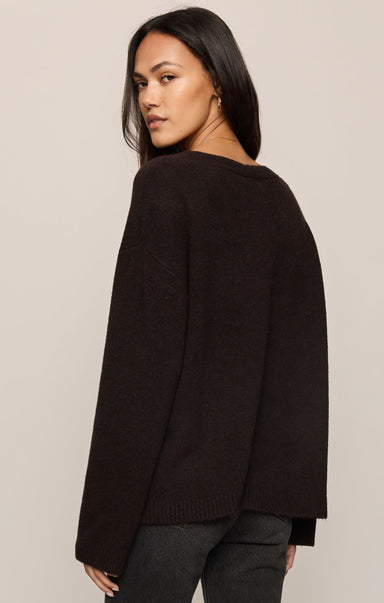 Woman wearing a black sweater against a beige background