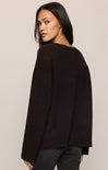 Woman wearing a black sweater against a beige background