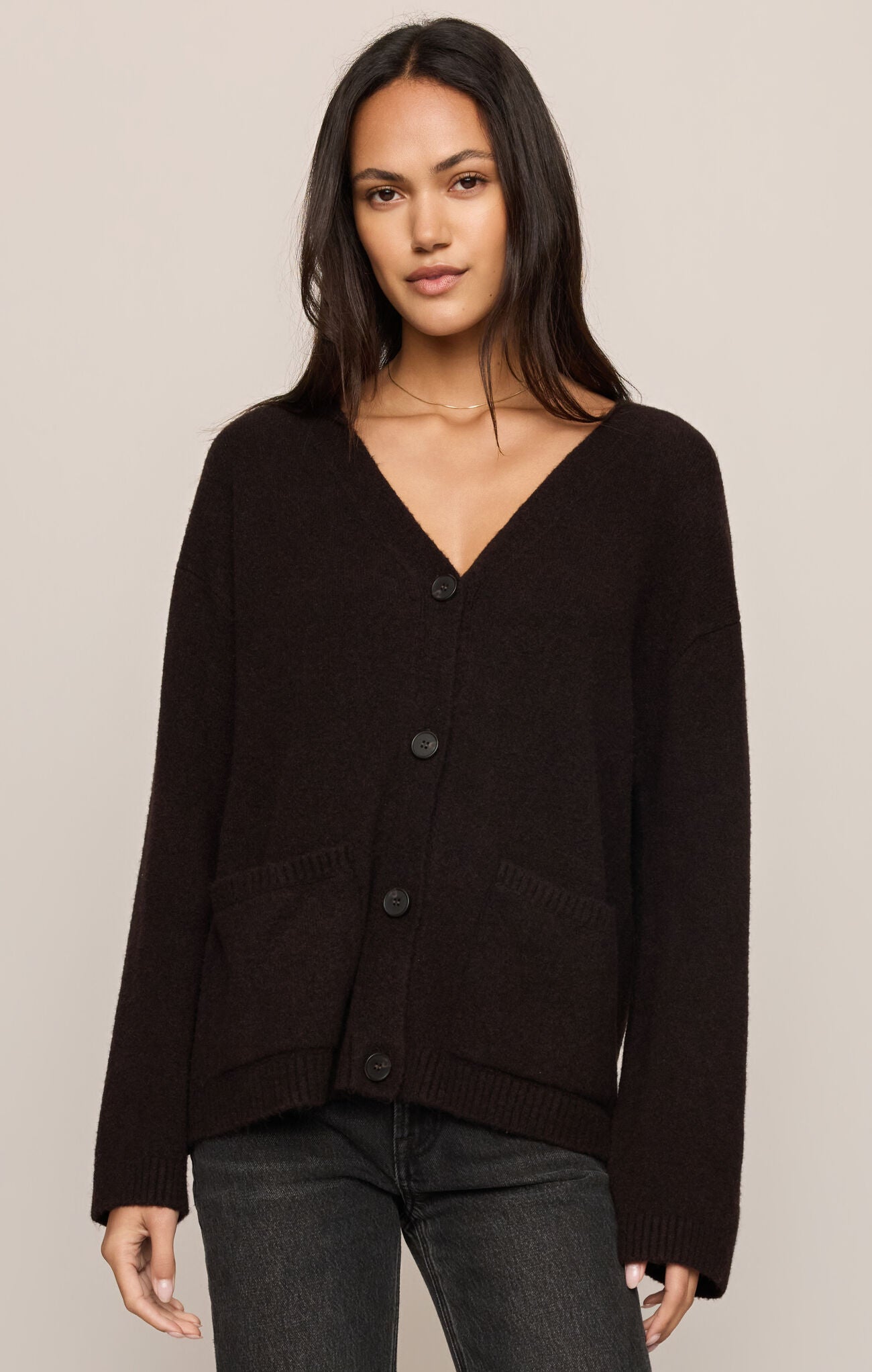 Woman wearing a black cardigan against a beige background
