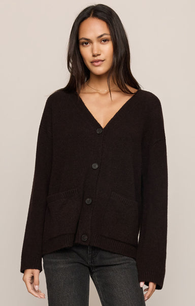 Woman wearing a black cardigan against a beige background