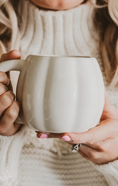 Person holding a white mug with a soft focus background