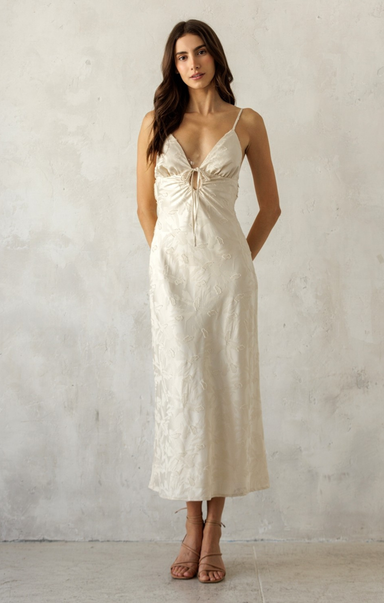 Woman wearing a white slip dress against a plain background