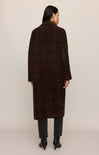 Person wearing a brown checkered coat on a beige background