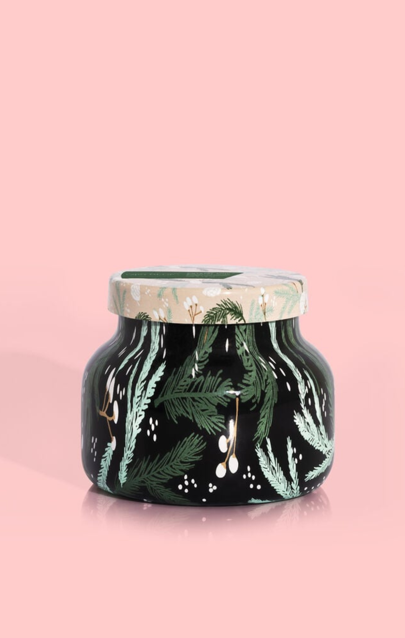 Candle jar with green leaf design on a pink background
