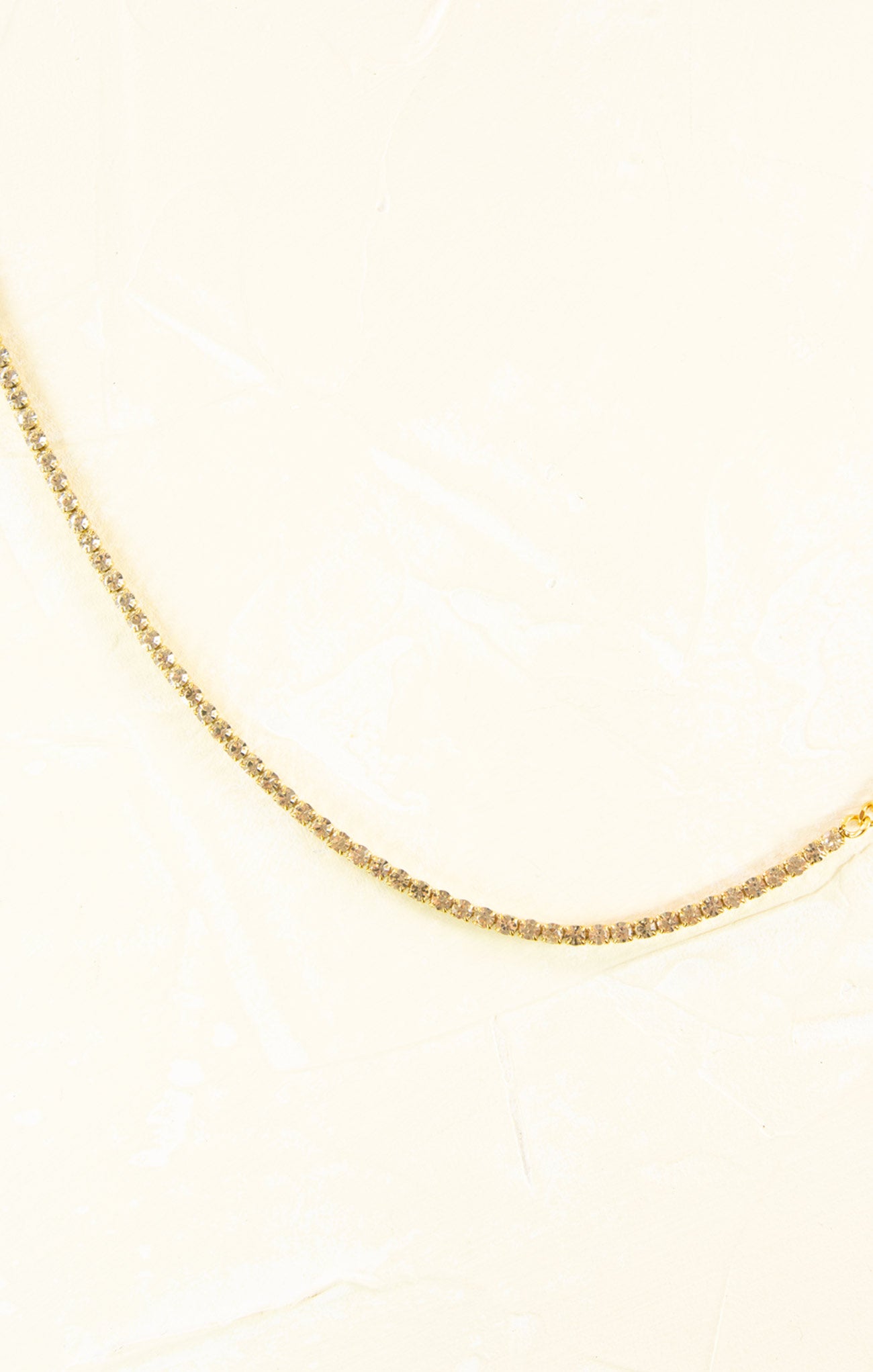 Gold chain necklace on a light beige background