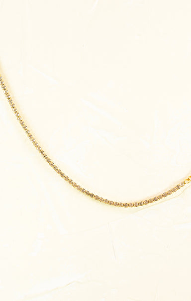Gold chain necklace on a light beige background