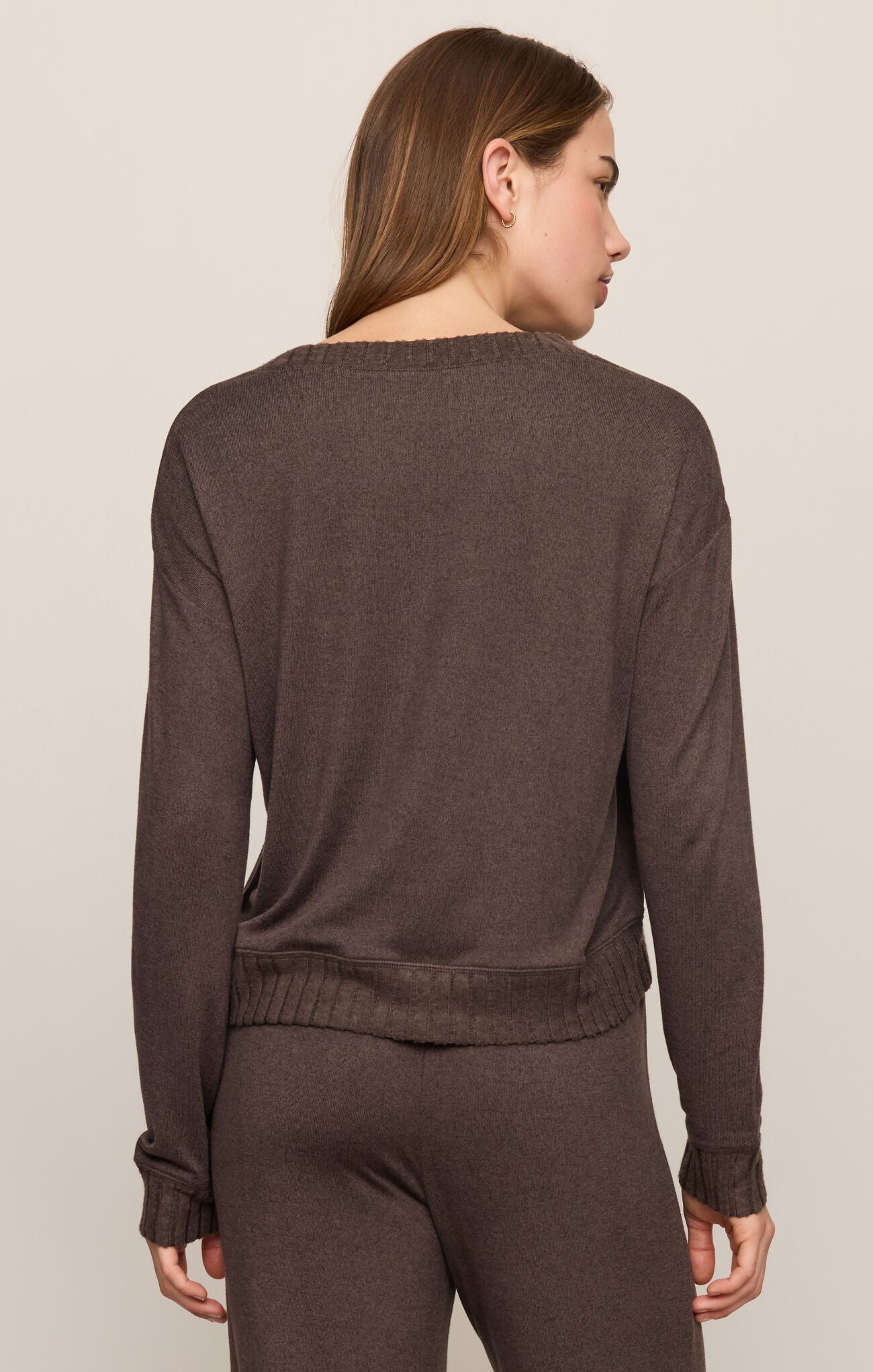 Woman wearing a brown sweater and pants set on a beige background