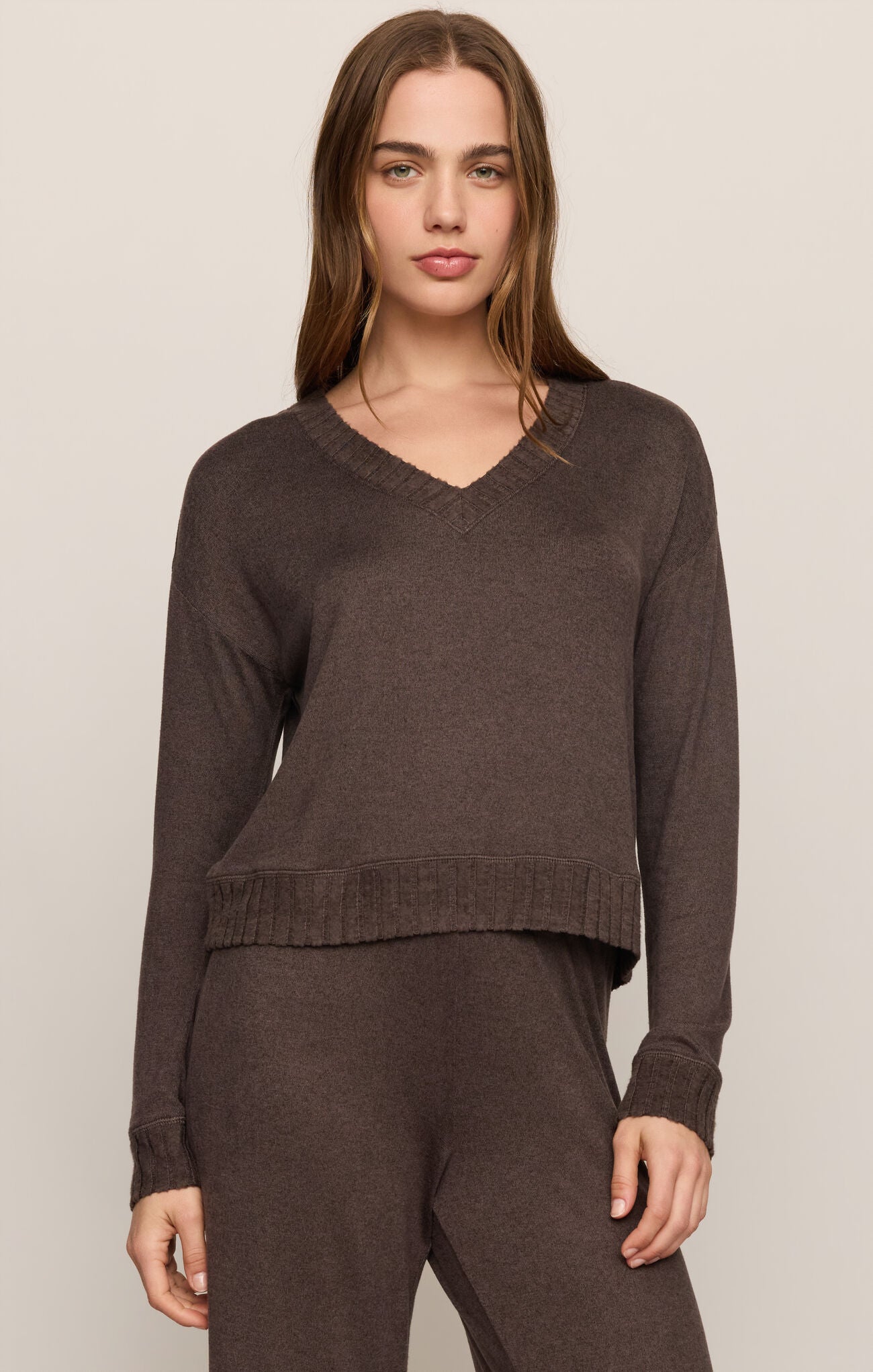 Woman wearing a brown sweater and pants on a beige background