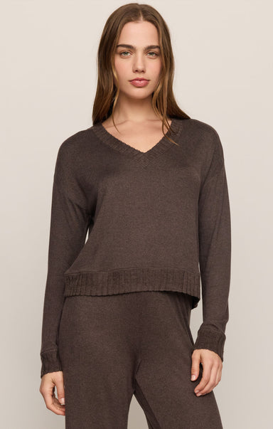 Woman wearing a brown sweater and pants on a beige background