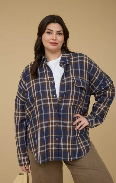 Woman wearing a plaid shirt over a white top on a beige background
