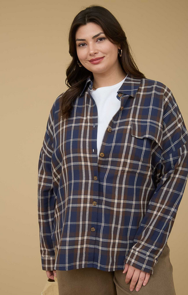 Woman wearing a blue and brown plaid shirt against a beige background