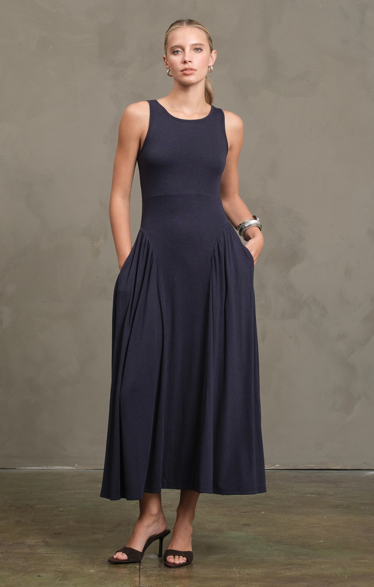 Woman wearing a navy blue sleeveless dress against a plain background