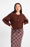 Woman wearing a brown knitted cardigan and plaid skirt on a white background