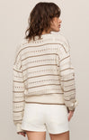 Woman wearing a striped sweater and white shorts against a plain background
