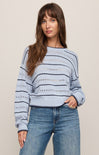 Woman wearing a blue and white striped sweater and jeans on a beige background