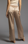 Beige satin pants worn by a person on a gray background