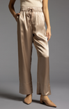 Beige satin pants worn by a person on a gray background