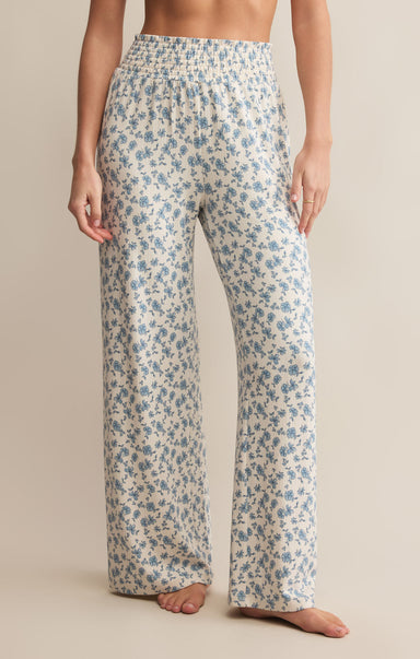 A pair of high-waisted, full-length pants with a smocked waistband and a blue floral pattern on a white background.