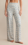 A pair of high-waisted, full-length pants with a smocked waistband and a blue floral pattern on a white background.