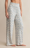 A pair of high-waisted, full-length pants with a smocked waistband and a blue floral pattern on a white background.