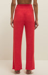 Red ribbed pants worn by a person on a beige background