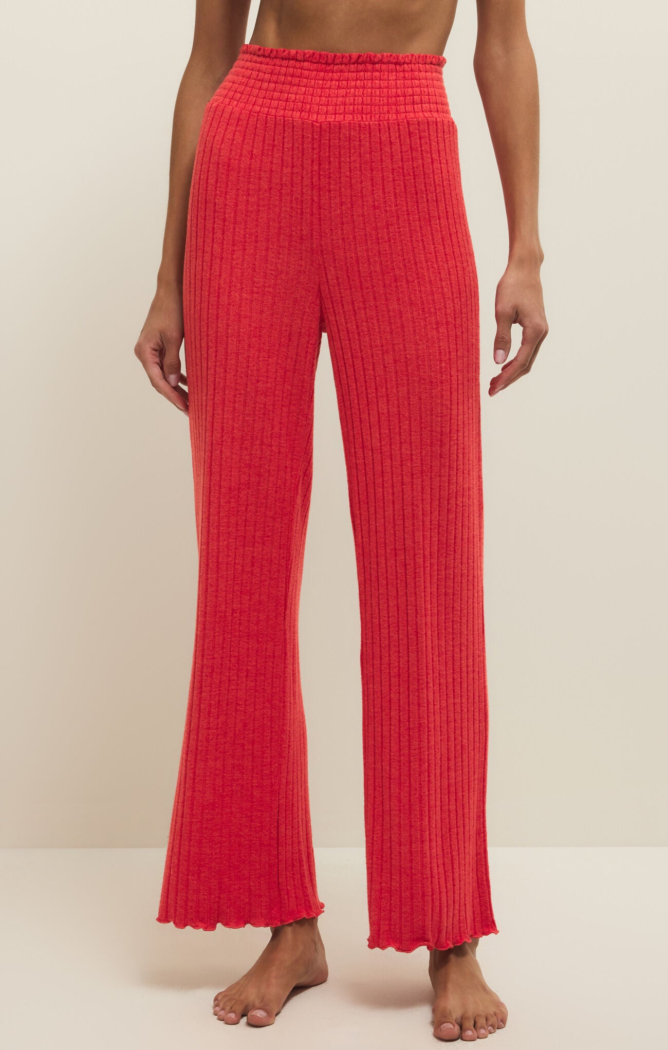 Red ribbed pants worn by a person on a beige background