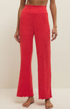 Red ribbed pants worn by a person on a beige background