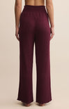 Maroon ribbed pants worn by a person on a beige background
