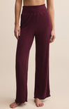 Maroon ribbed pants worn by a person on a beige background