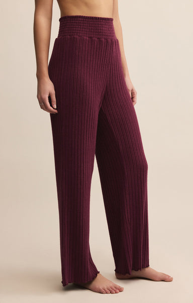 Maroon ribbed pants worn by a person on a beige background