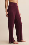 Maroon ribbed pants worn by a person on a beige background