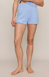 Person wearing light blue checkered shorts on a beige background