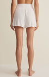 White pleated shorts worn by a person on a beige background