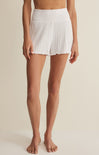Person wearing white ribbed shorts on a beige background