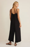 Woman wearing a black jumpsuit on a beige background