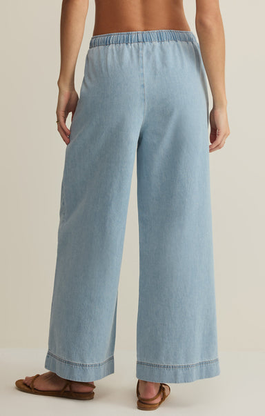 Light blue denim pants worn by a person on a beige background