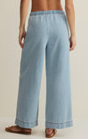 Light blue denim pants worn by a person on a beige background