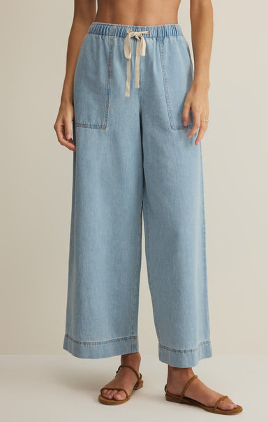 Light blue denim pants worn by a person on a beige background