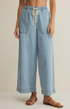 Light blue denim pants worn by a person on a beige background