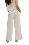 Person wearing a light-colored sleeveless top and wide-leg pants on a white background
