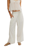 Woman wearing a white outfit with wide-leg pants on a white background