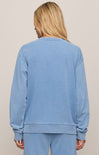 Person wearing a blue sweatshirt and pants set against a beige background