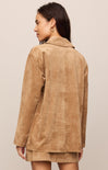 Woman wearing a brown suede jacket against a beige background