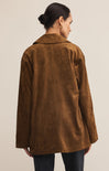 Person wearing a brown suede jacket on a plain background