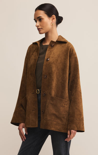 Woman wearing a brown suede coat against a beige background
