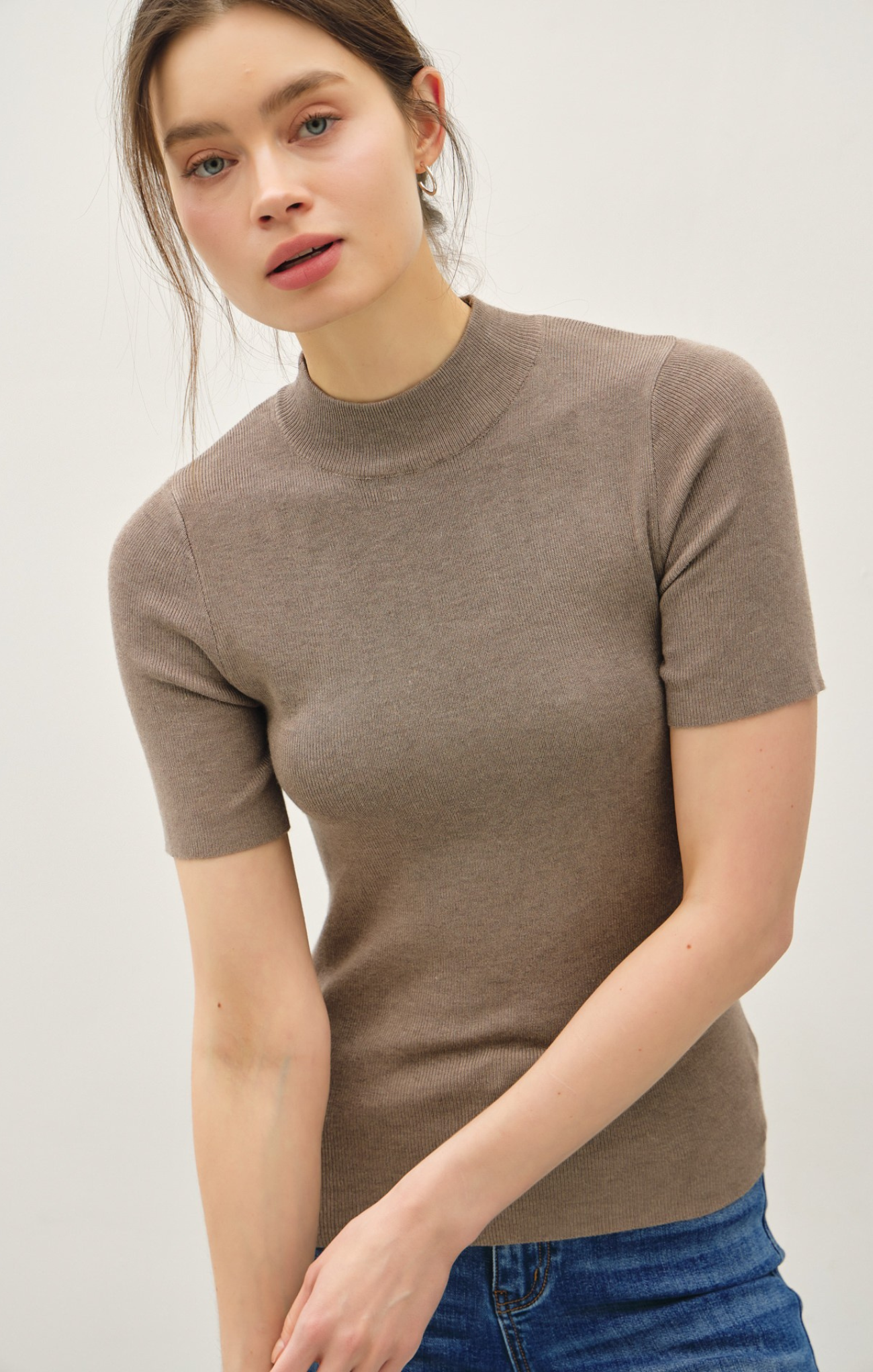 Woman wearing a brown short-sleeve top against a white background