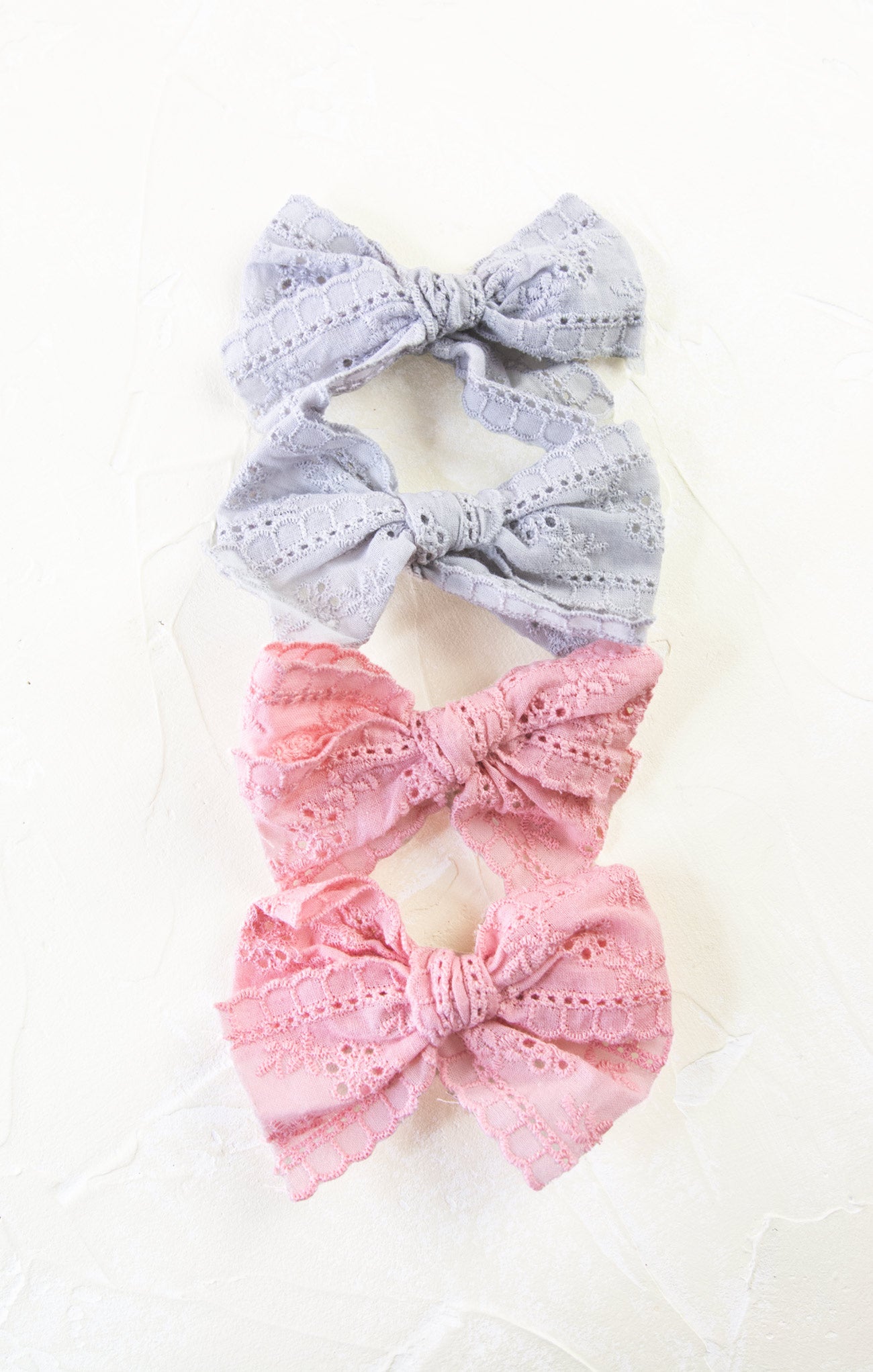 Three decorative bows, two gray and one pink, on a white background