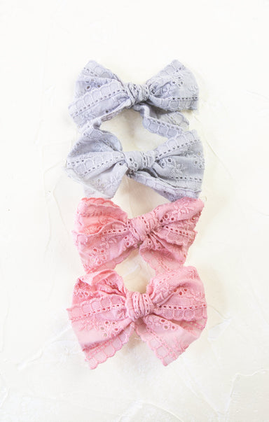 Three decorative bows, two gray and one pink, on a white background