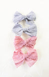 Three decorative bows, two gray and one pink, on a white background