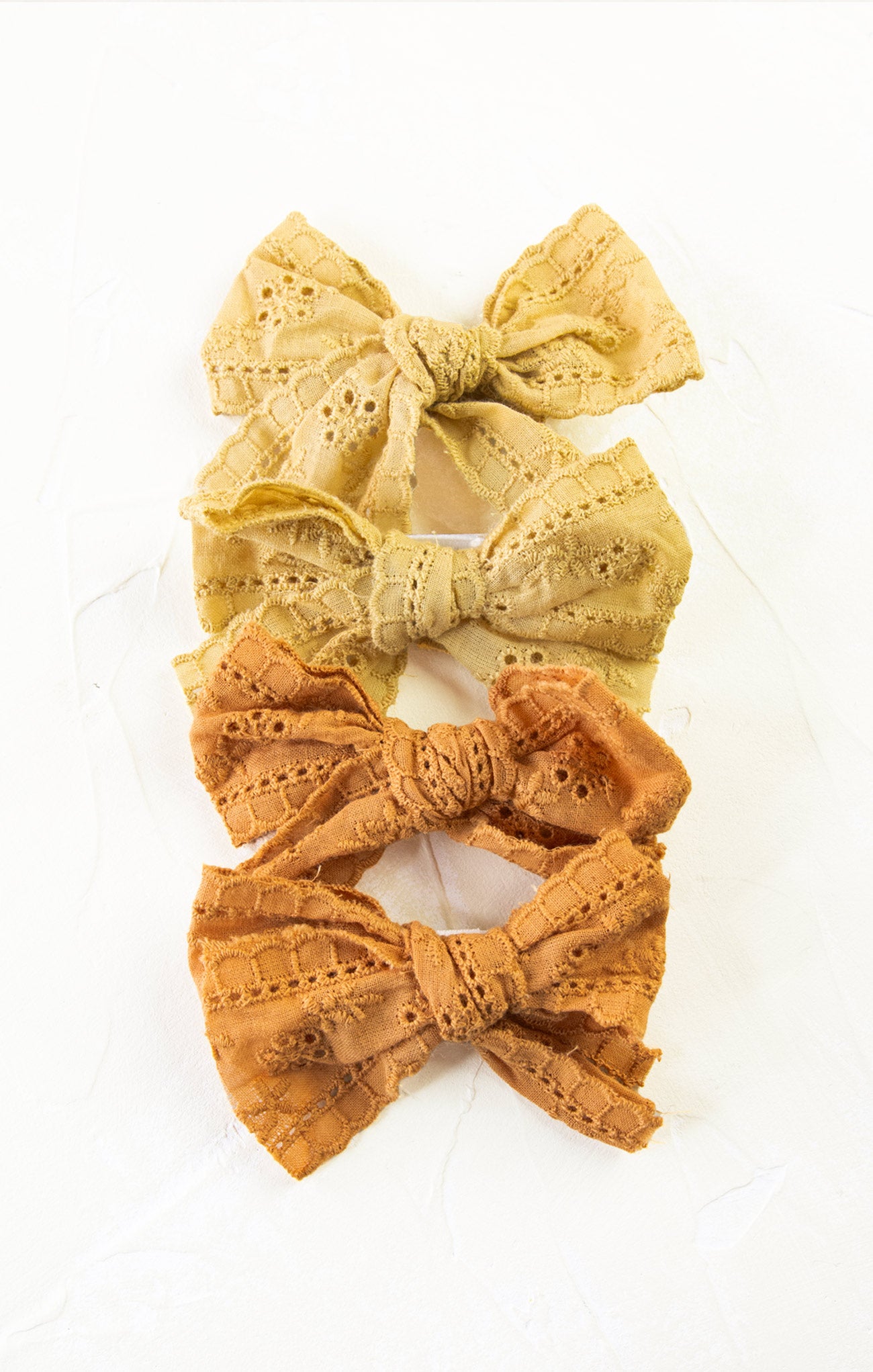 Three lace bows in yellow, green, and orange on a white background